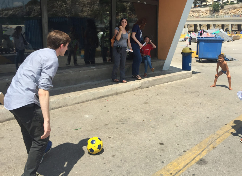 Journalism student Harrison Blackman plays soccer with a young refugee in Athens