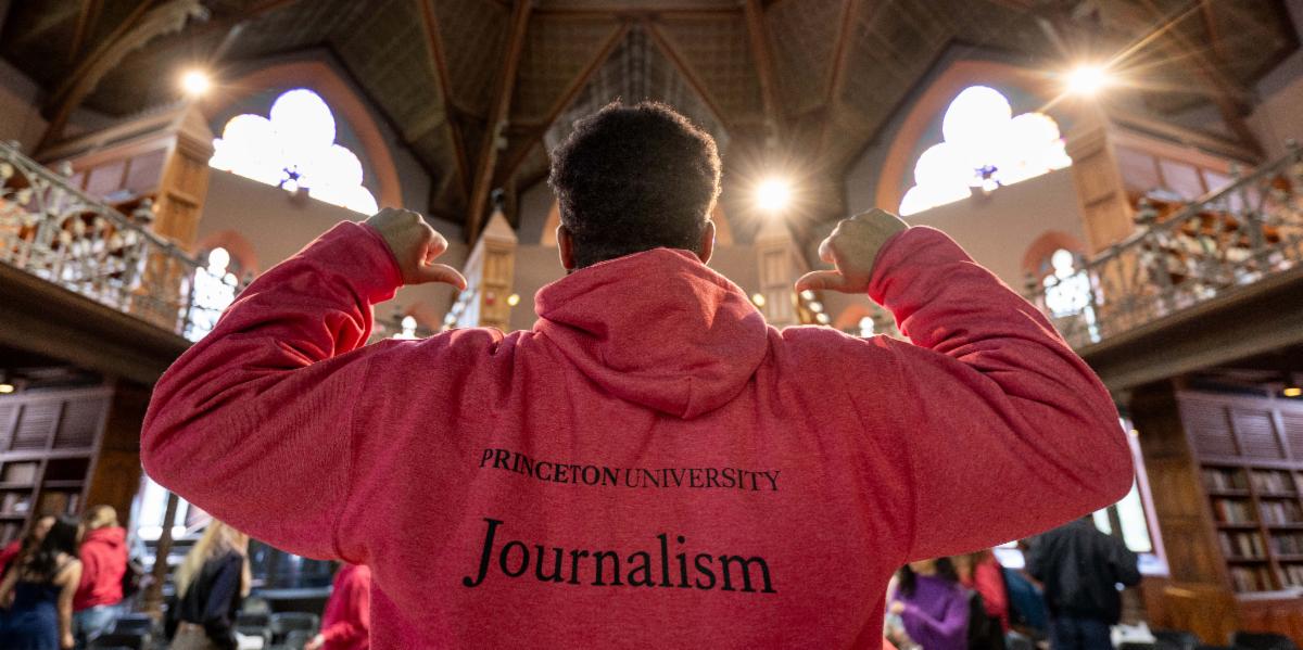Student wearing Journalism sweatshirt standing in East Pyne Rotunda.